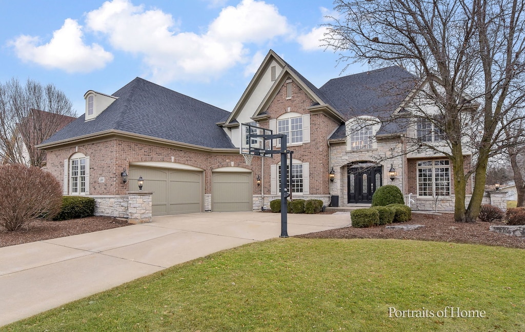 french country inspired facade featuring a garage and a front lawn