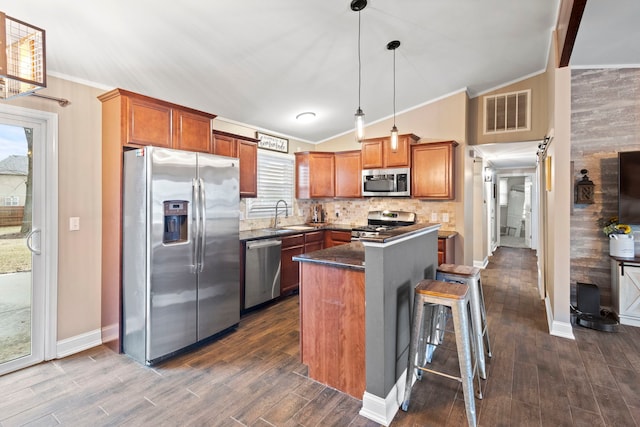 kitchen with lofted ceiling, sink, appliances with stainless steel finishes, a kitchen island, and pendant lighting