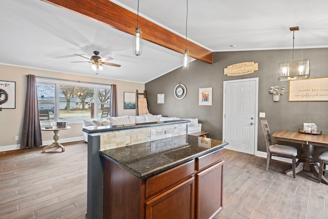 kitchen featuring pendant lighting, light hardwood / wood-style flooring, ceiling fan, vaulted ceiling with beams, and dark stone counters