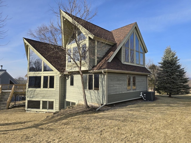 view of side of home with central AC unit and a lawn