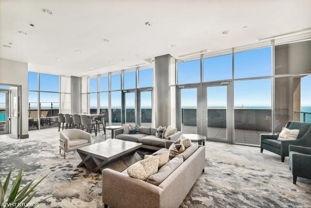 living room featuring a wall of windows, a high ceiling, and a water view