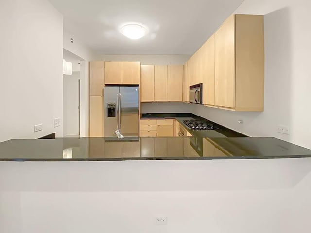 kitchen featuring dark stone countertops, kitchen peninsula, light brown cabinets, and black appliances