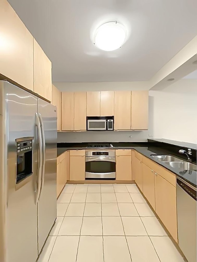 kitchen with sink, light tile patterned floors, light brown cabinets, and appliances with stainless steel finishes