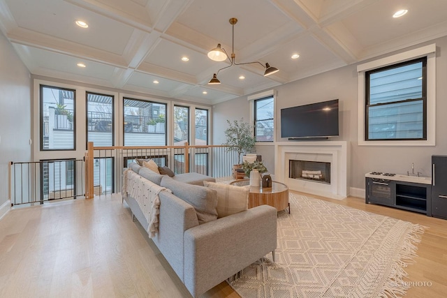 living room with crown molding, coffered ceiling, beam ceiling, and light hardwood / wood-style floors