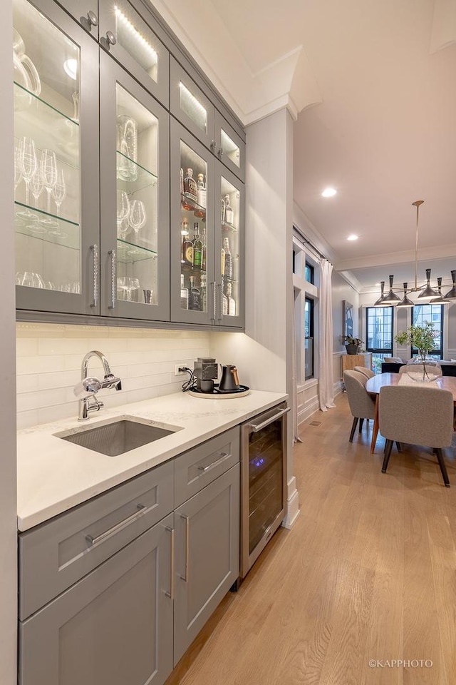 bar with wine cooler, sink, ornamental molding, and gray cabinetry