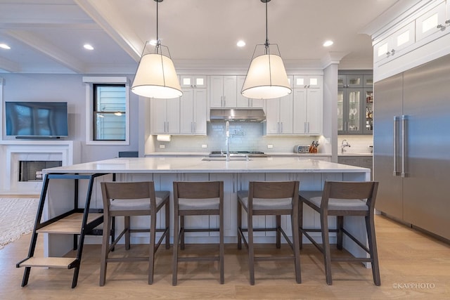 kitchen with a large island, hanging light fixtures, white cabinetry, and stainless steel built in fridge