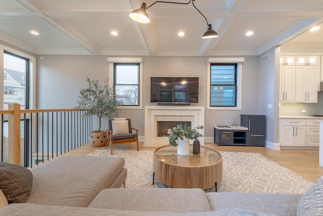 living room featuring ornamental molding, coffered ceiling, beam ceiling, and light hardwood / wood-style flooring