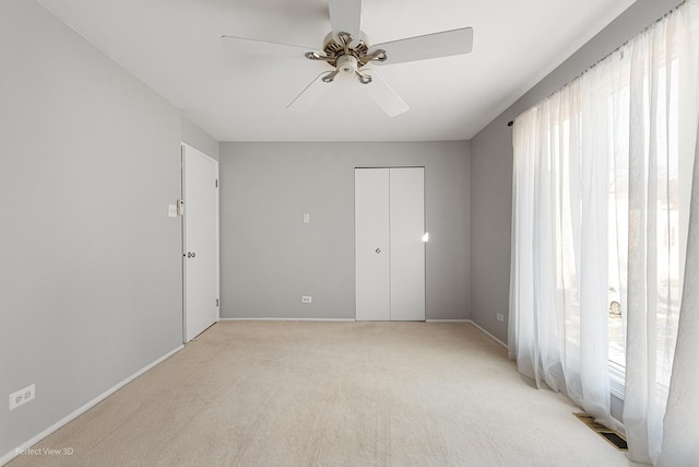 unfurnished bedroom with light carpet, a closet, and ceiling fan