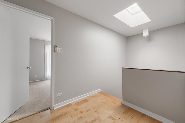 unfurnished room featuring light hardwood / wood-style flooring and a skylight