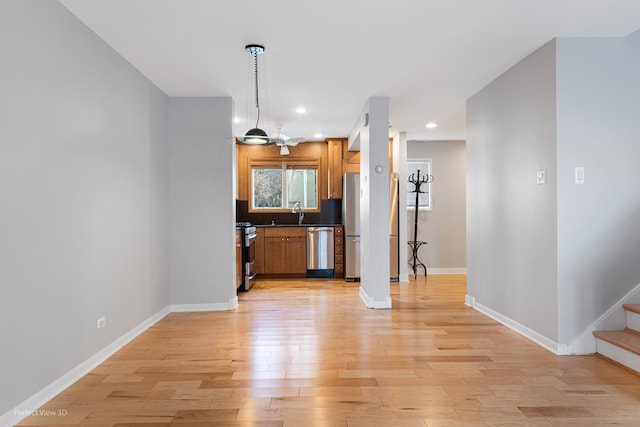 kitchen with sink, decorative backsplash, hanging light fixtures, stainless steel appliances, and light wood-type flooring