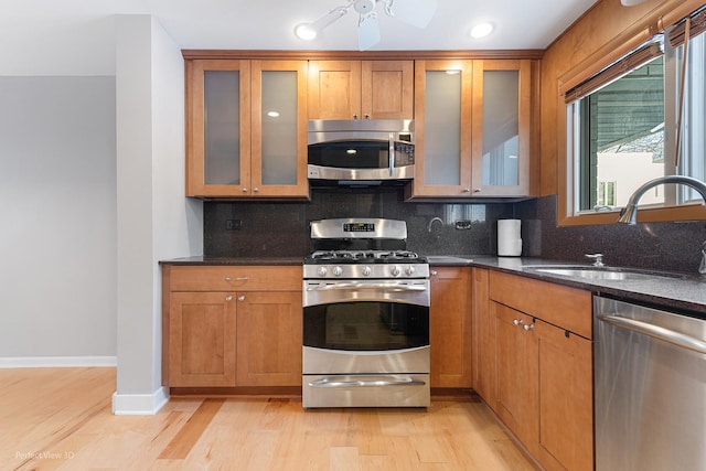 kitchen featuring stainless steel appliances, sink, decorative backsplash, and dark stone counters