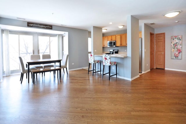 kitchen featuring stainless steel appliances, a breakfast bar, hardwood / wood-style floors, and kitchen peninsula