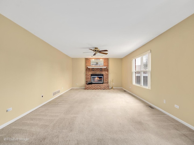 unfurnished living room featuring a fireplace, light colored carpet, and ceiling fan