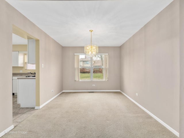 carpeted spare room with a notable chandelier