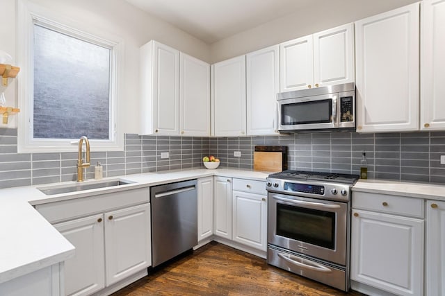 kitchen with light countertops, appliances with stainless steel finishes, a sink, and white cabinetry