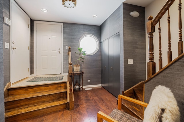 foyer featuring dark wood-style floors, visible vents, baseboards, and stairs