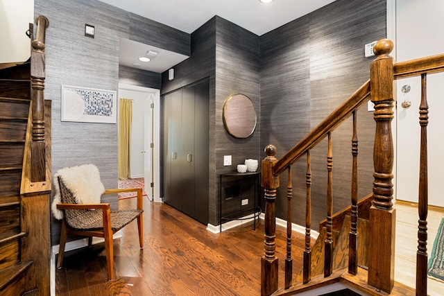 interior space featuring stairs, wood finished floors, baseboards, and wallpapered walls