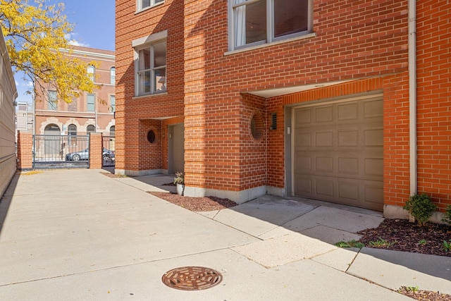 view of exterior entry with concrete driveway, brick siding, and an attached garage