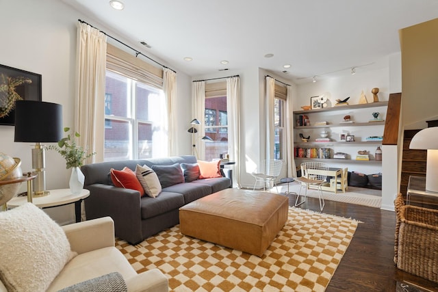 living area with rail lighting, visible vents, and wood finished floors