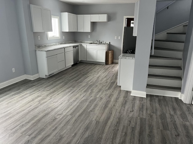 kitchen with sink, white cabinetry, black fridge, dark hardwood / wood-style flooring, and stainless steel dishwasher