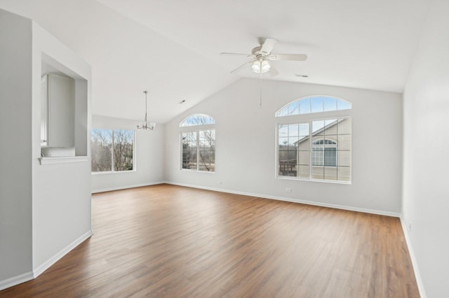 spare room with lofted ceiling, ceiling fan with notable chandelier, and dark hardwood / wood-style flooring