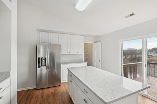 kitchen with stainless steel refrigerator with ice dispenser, lofted ceiling, a kitchen island, and white cabinets