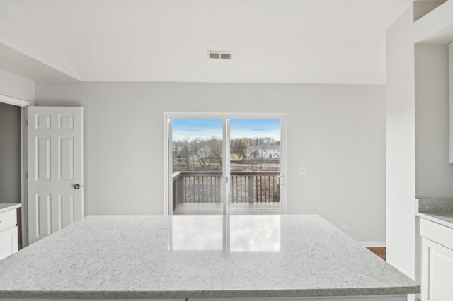 kitchen featuring light stone counters, a kitchen island, and white cabinets