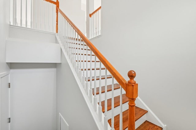 stairs featuring hardwood / wood-style floors and a high ceiling