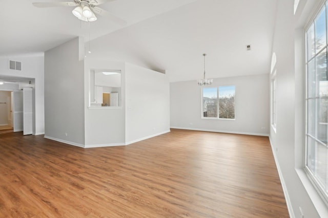 unfurnished living room featuring hardwood / wood-style flooring, ceiling fan with notable chandelier, and high vaulted ceiling