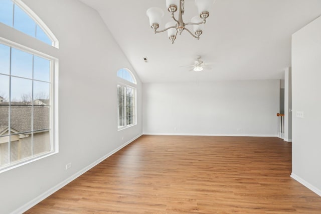 empty room featuring ceiling fan with notable chandelier, high vaulted ceiling, and light hardwood / wood-style floors