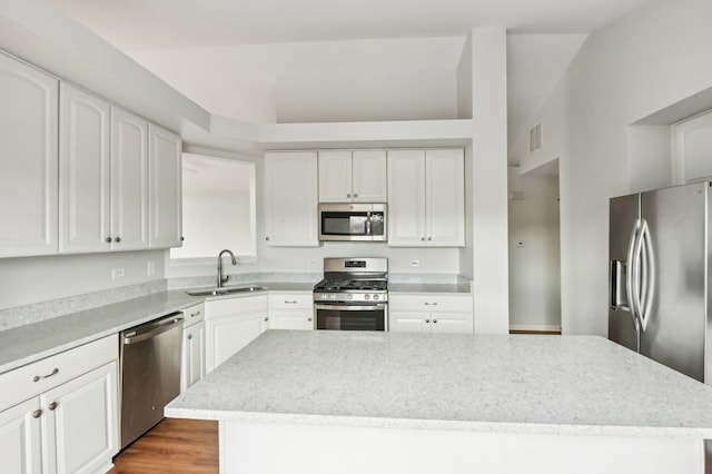 kitchen featuring sink, dark wood-type flooring, stainless steel appliances, white cabinets, and a kitchen island