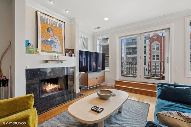 living room featuring ornamental molding, a wealth of natural light, hardwood / wood-style floors, and a fireplace