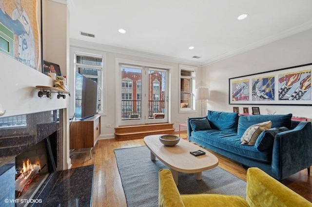 living room featuring ornamental molding, a fireplace, and light wood-type flooring