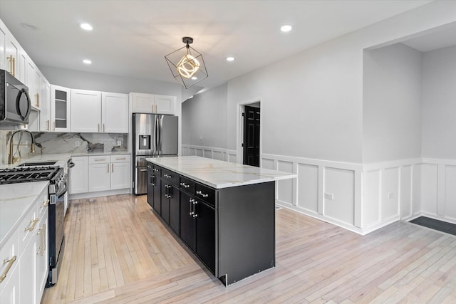 kitchen with pendant lighting, white cabinets, decorative backsplash, a center island, and stainless steel appliances