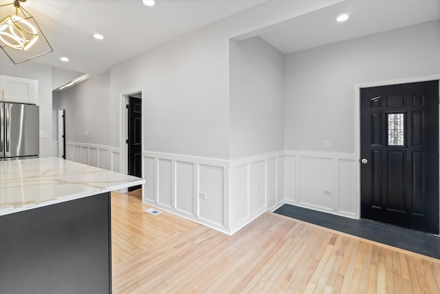 foyer entrance with a notable chandelier and light hardwood / wood-style floors