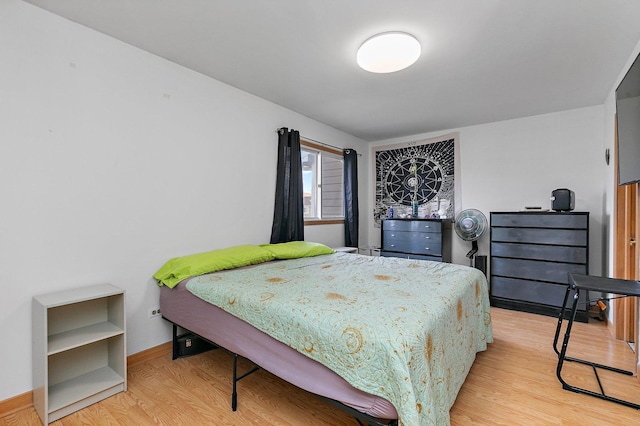 bedroom featuring light wood finished floors and baseboards