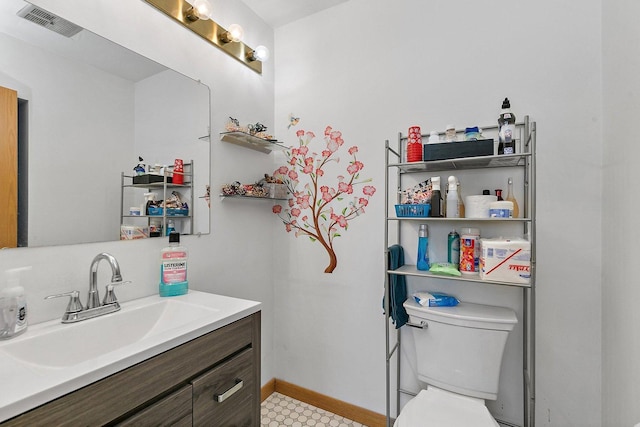 bathroom featuring visible vents, vanity, toilet, and baseboards