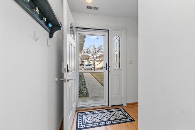 doorway to outside featuring wood finished floors, visible vents, and baseboards