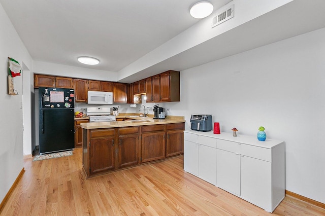 kitchen featuring white appliances, visible vents, light wood-style flooring, light countertops, and a sink