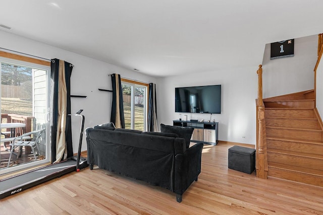 living area with stairs, light wood finished floors, visible vents, and baseboards