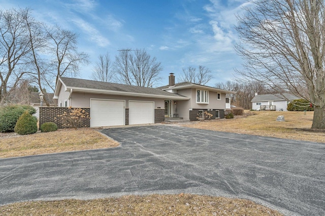 split level home featuring a garage and a front lawn