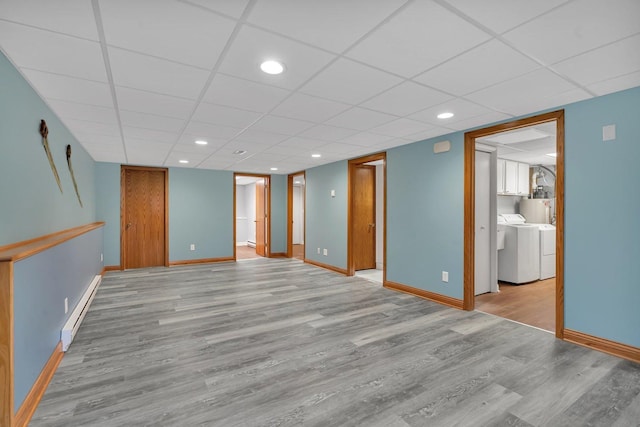 interior space featuring a paneled ceiling, washer and clothes dryer, light wood-type flooring, and a baseboard heating unit