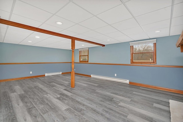 basement with hardwood / wood-style floors, a baseboard radiator, and a paneled ceiling