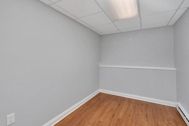 spare room with a baseboard radiator, wood-type flooring, and a paneled ceiling