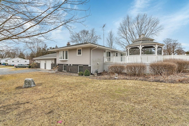 view of side of home featuring a garage, a gazebo, and a lawn