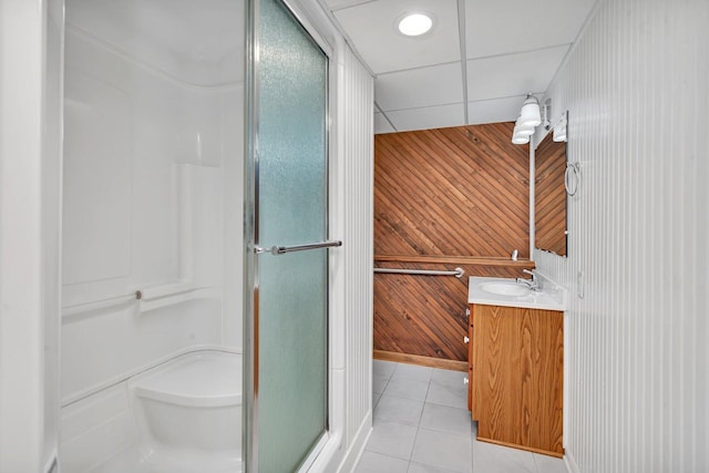 bathroom featuring a paneled ceiling, wooden walls, an enclosed shower, vanity, and tile patterned floors