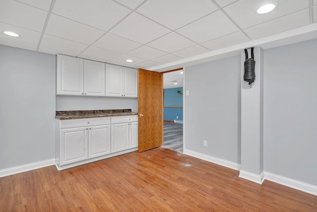 interior space featuring baseboard heating, a paneled ceiling, and light hardwood / wood-style floors