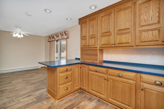 kitchen with baseboard heating, kitchen peninsula, decorative backsplash, and hardwood / wood-style flooring