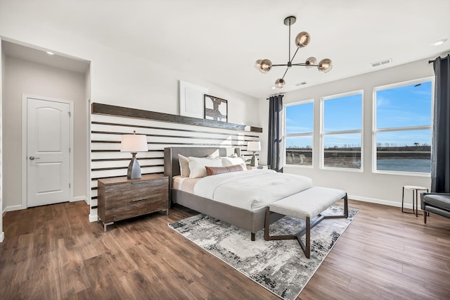 bedroom with a water view, a chandelier, and dark wood-type flooring