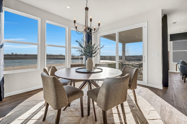 dining space with a water view, dark hardwood / wood-style flooring, and an inviting chandelier